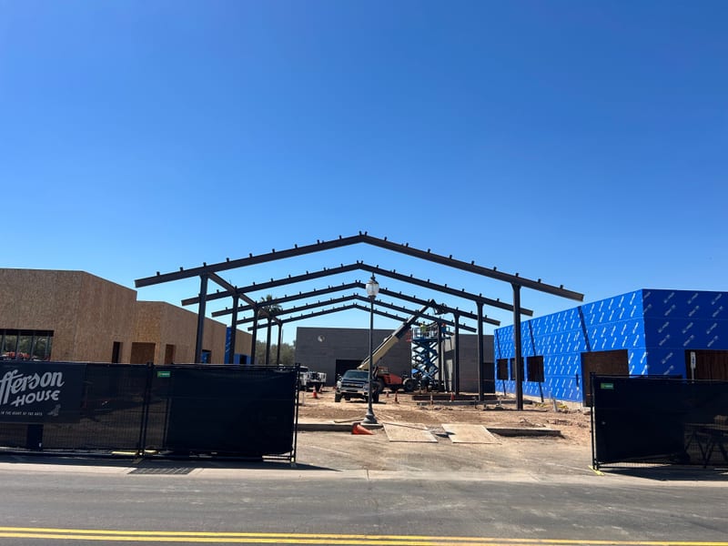 The black-steel gable canopy frame erected at Jefferson House with the Jefferson House banner on the fence, April 2026