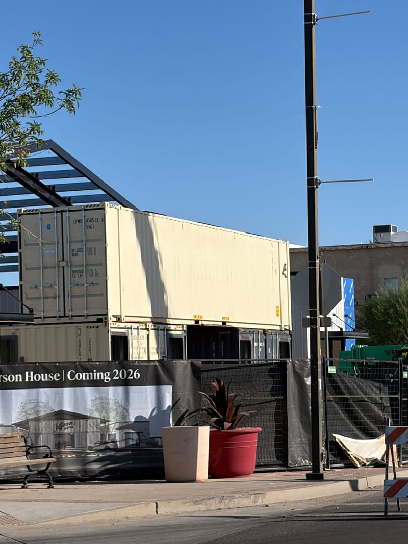 Shipping-container shops stacked into place at Jefferson House with the Coming 2026 banner, June 2026