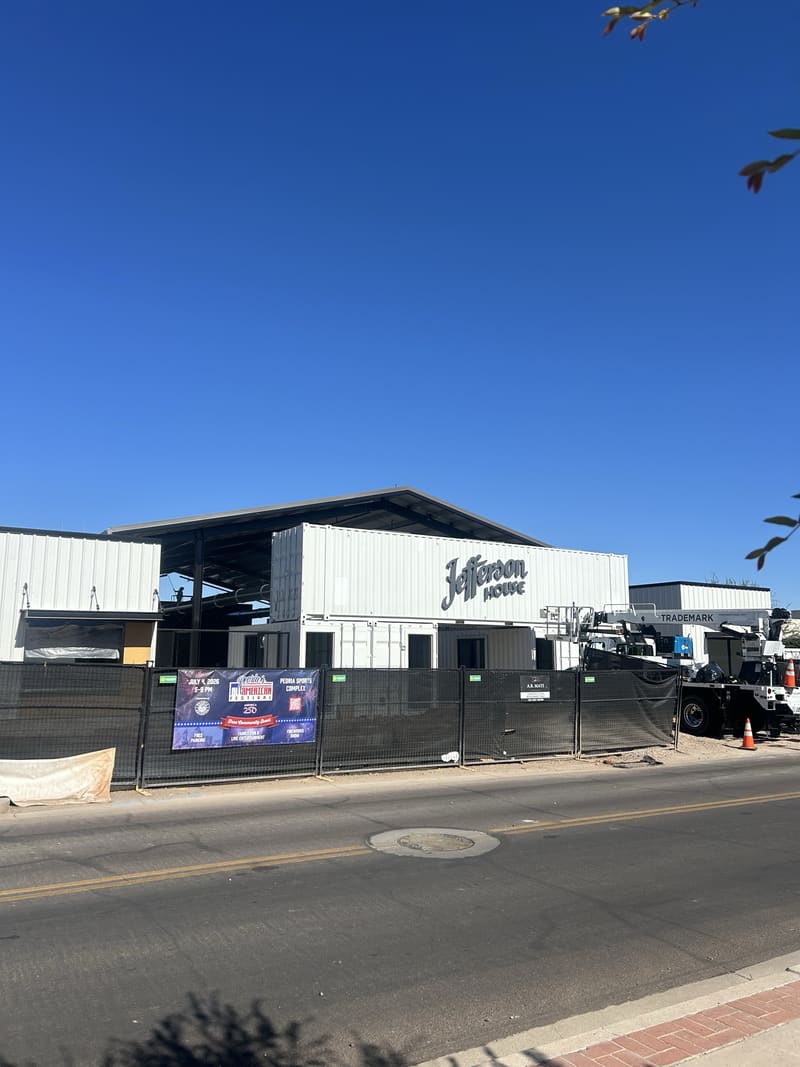 The white container shops at Jefferson House with the painted Jefferson House script logo, seen from Jefferson Street, July 2026
