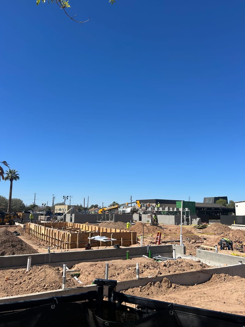 Poured footings and the first concrete-block walls rising at the Jefferson House site with a crane behind